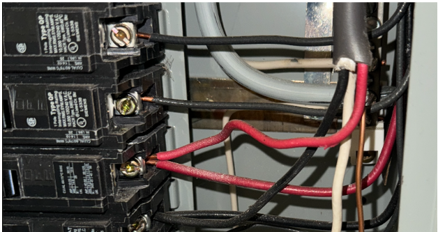 Close-up of two electrical conductors connected to one circuit breaker terminal in a residential electrical panel